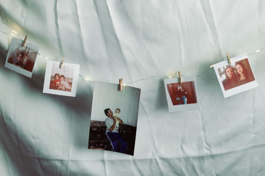Old family photos are pegged to a string with a white sheet background.