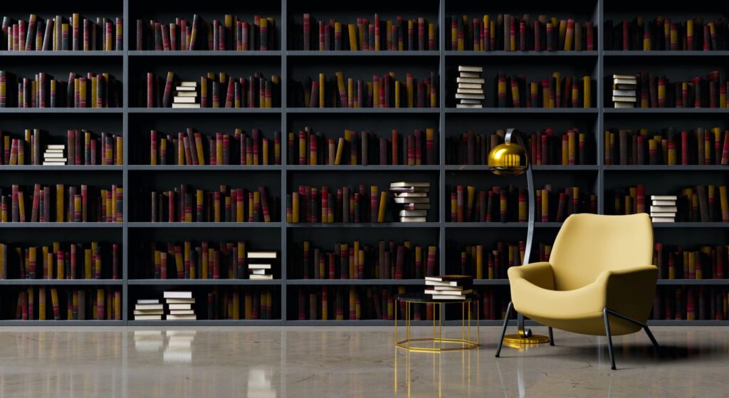 an empty arm chair with a lamp beside it in front of a bookcase that extends along the wall