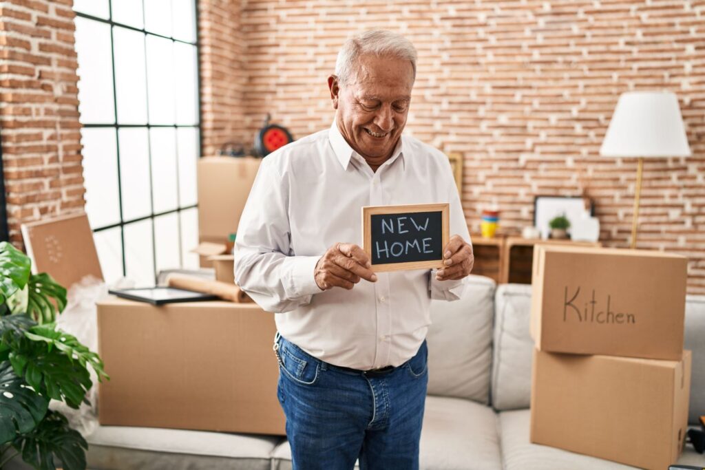 senior-man-smiling-confident-holding-blackboard-new-home