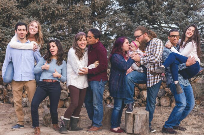 5 or 6 couples in their 30s and 40s posing for a photo in the forest