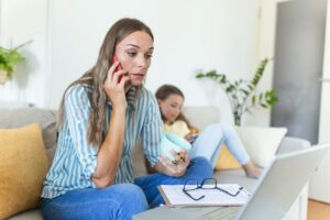 A middle aged woman talks on the phone to her advisor. She is perturbed.